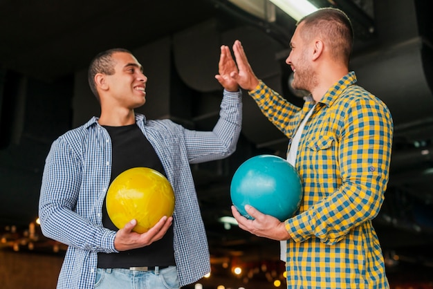 Hommes tenant des boules de bowling colorées