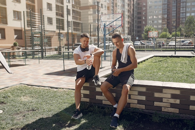 Photo gratuite les hommes en tenue de sport se reposent après une formation dans un parc