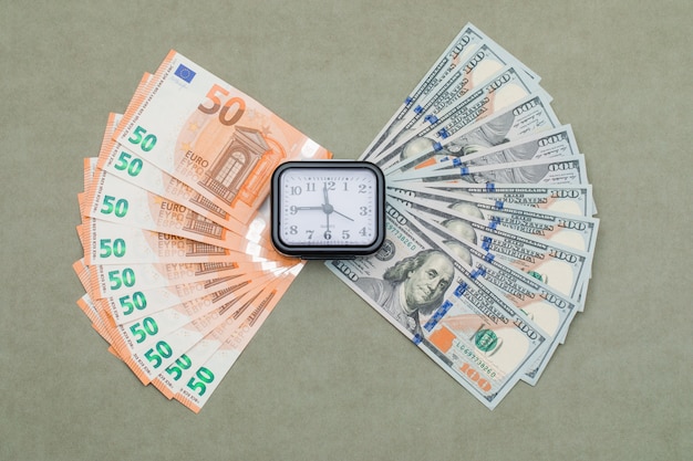 Photo gratuite horloge, dollar et euro factures sur table gris vert.