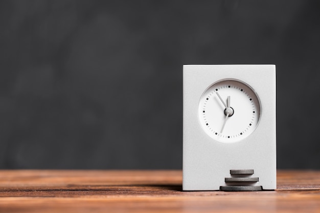 Horloge rectangulaire moderne sur un bureau en bois texturé sur fond noir