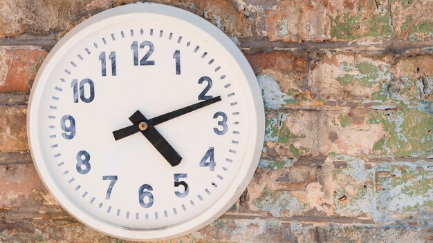Horloge ronde accrochée au mur de briques