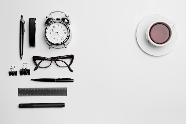 L'horloge, le stylo et les lunettes sur blanc