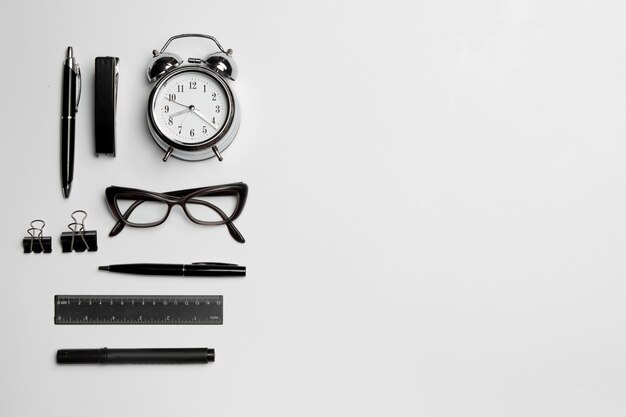 L'horloge, le stylo et les lunettes sur une surface blanche