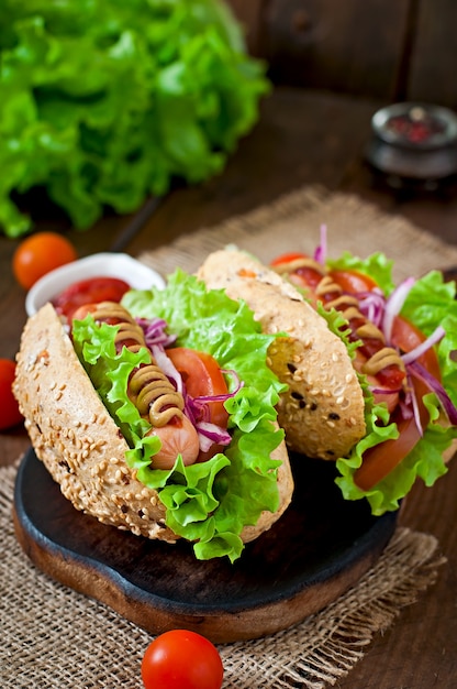 Hot-dog avec moutarde ketchup et laitue sur table en bois.