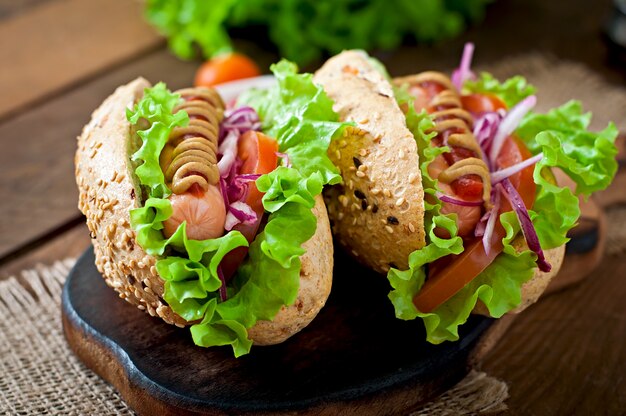 Hot-dog avec moutarde ketchup et laitue sur table en bois.