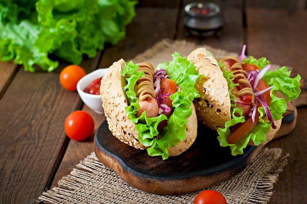 Hot-dog avec moutarde ketchup et laitue sur table en bois.