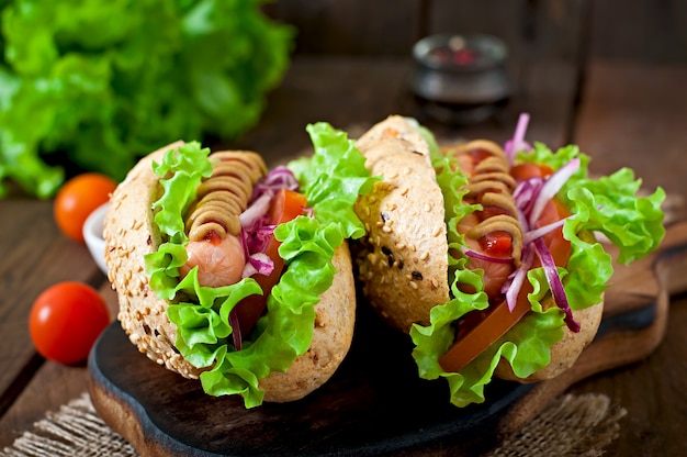 Hot-dog avec moutarde ketchup et laitue sur table en bois.