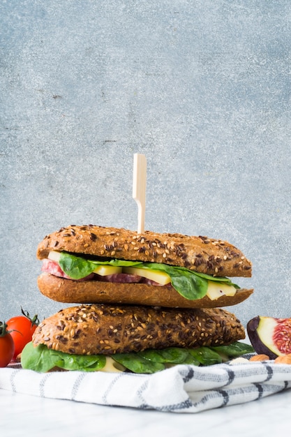 Hot-dog; tranches de figue; amandes et tomates cerises sur une serviette à carreaux contre un mur de béton