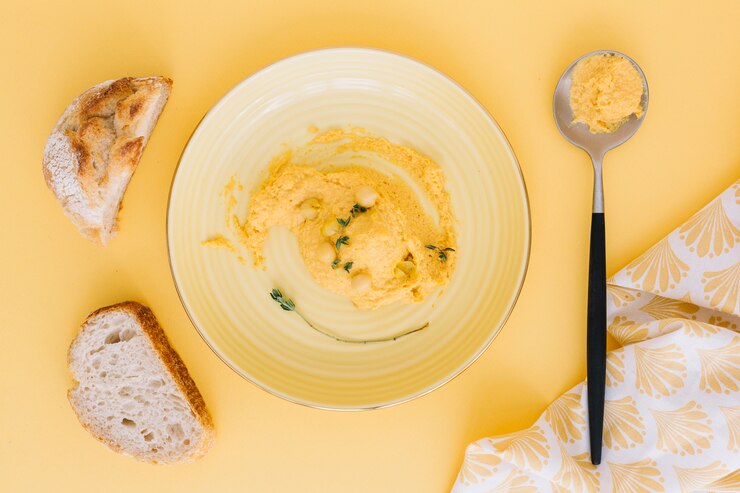 Photo gratuit houmous sur assiette et cuillère avec des tranches de pain sur fond beige