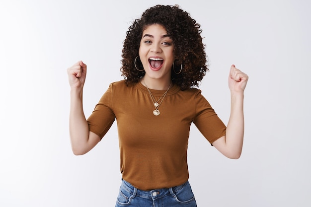 Hourra bonne nouvelle. Séduisante jeune fille heureuse et réussie, cheveux bouclés noirs, encourageant un ami soutenant l'index de serrage des doigts levés geste de victoire célébrant un ami félicitant souriant joyeusement