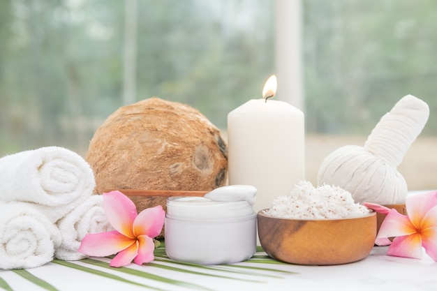 Huile de coco, feuilles tropicales et noix de coco fraîches. Produits de noix de coco Spa sur une surface en bois clair.