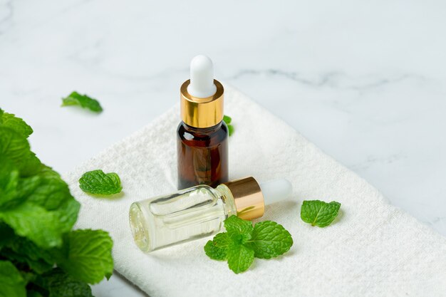 Huile essentielle de menthe poivrée en bouteille avec de la menthe verte fraîche