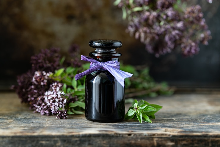 Photo gratuit huile essentielle d'origan en bouteille en verre sur fond de bois. copie espace