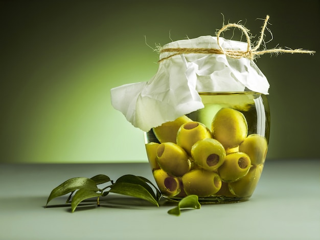 Photo gratuite l'huile d'olive et la branche d'olivier sur table en bois