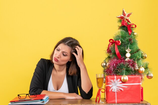 L'humeur du nouvel an avec une belle femme d'affaires confuse au sujet de quelque chose et assise à une table au bureau