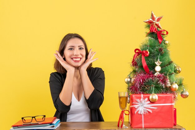 L'humeur du nouvel an avec une belle femme d'affaires heureuse et satisfaite assise à une table au bureau