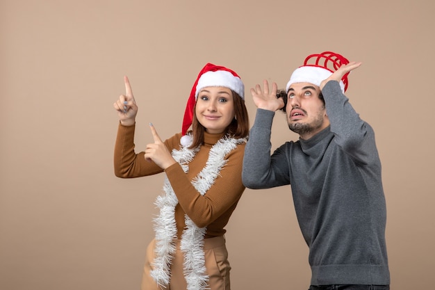 L'humeur de Noël avec excité cool satisfait joli couple portant des chapeaux de père Noël rouge pointant au-dessus