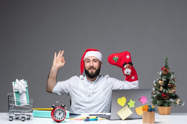 L'humeur de Noël avec jeune adulte avec chapeau de père Noël et porter des chaussettes de Noël à sa main en faisant un geste correct au bureau sur fond blanc