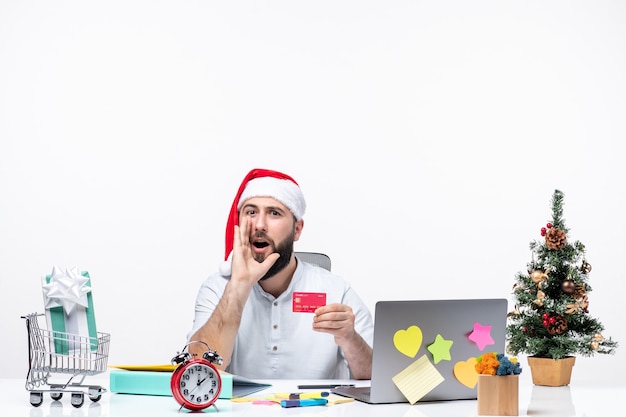 humeur de noël avec un jeune adulte avec un chapeau de père noël et tenant une carte bancaire et appelant quelqu'un au bureau