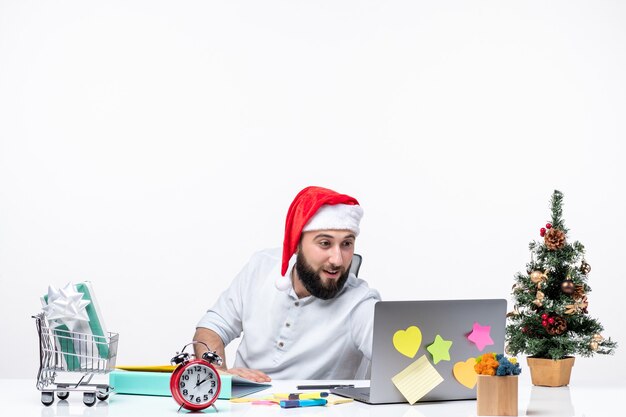 humeur de noël avec un jeune adulte positif avec un chapeau de père noël vérifiant ses mails au bureau