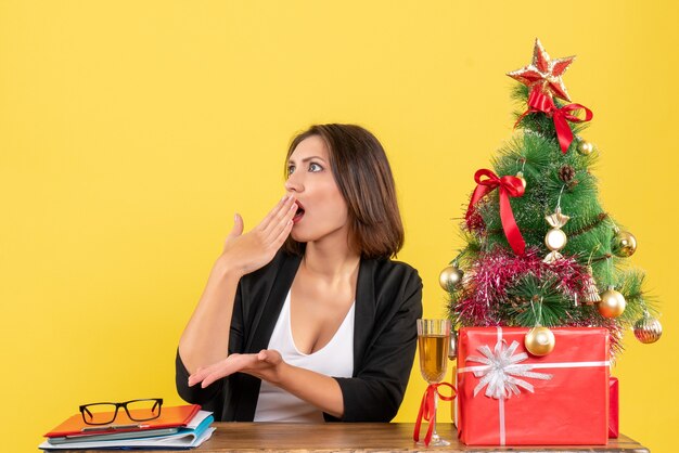 L'humeur de Noël avec jeune femme d'affaires émotionnelle confus assis à une table au bureau