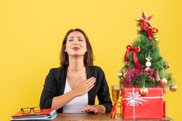 L'humeur de Noël avec une jeune femme d'affaires satisfaite heureuse rêvant de quelque chose sur le jaune