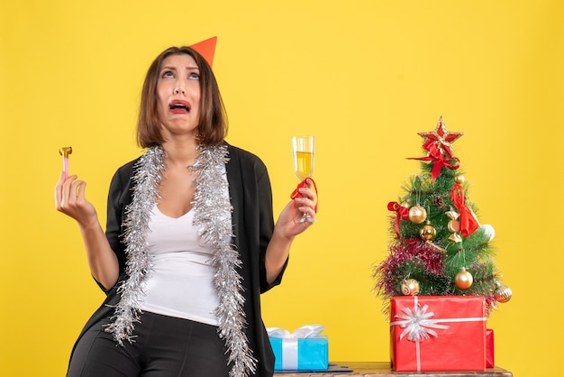 L'humeur de Noël avec peur belle dame tenant du vin et levant les yeux dans le bureau sur jaune