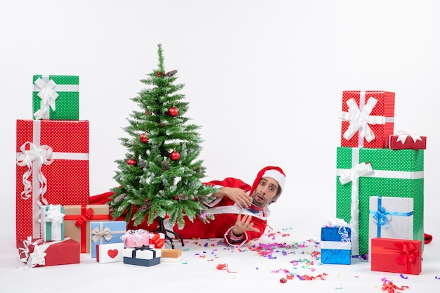 L'humeur de vacances avec le père Noël couché derrière l'arbre de Noël près de cadeaux sur fond blanc