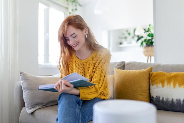 Humidificateur domestique à la maison sur la table près de femme lisant sur le canapé