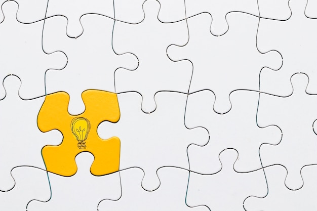 Icône idée sur la pièce de puzzle jaune connectée avec la toile de fond de puzzle grille blanche