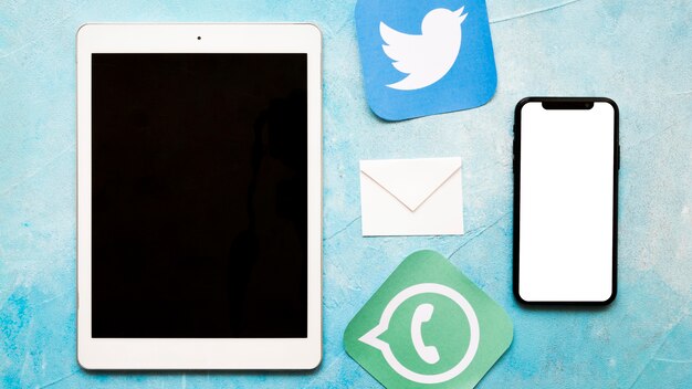 Icônes de médias sociaux avec téléphone portable et tablette numérique sur fond de texture peinte bleu