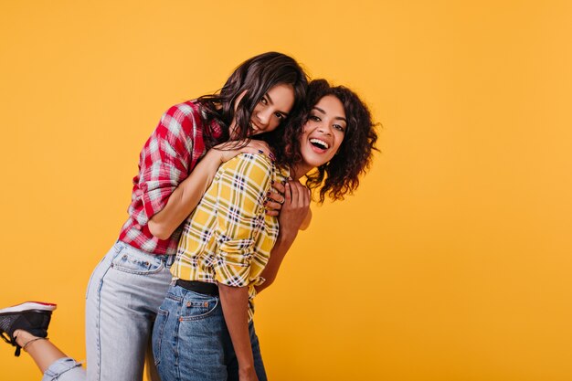 Idées de jeunes filles élégantes. Dame en chemisier rouge a sauté sur sa sœur pour le plaisir.