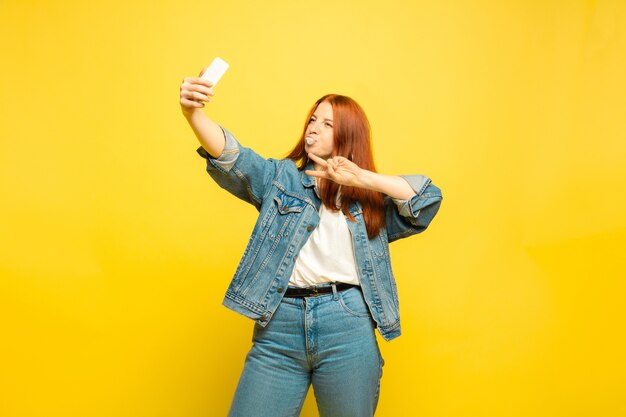 Il est plus facile d'être suiveur. Besoin de vêtements minimum pour selfie. Portrait de femme caucasienne sur fond jaune. Beau modèle de cheveux roux féminin. Concept d'émotions humaines, expression faciale, ventes, publicité.