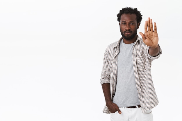 Photo gratuite il est temps de s'arrêter et de réfléchir. homme barbu afro-américain à l'air sérieux avec un geste d'arrêt