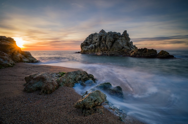 Photo gratuit île rocheuse près de la plage d'une belle mer au coucher du soleil