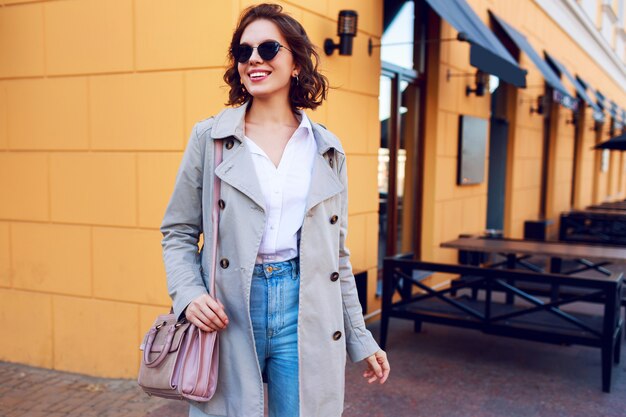 Image d'automne d'une femme charmante élégante en manteau beige marchant en plein air. Look de rue à la mode.