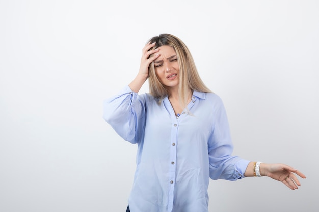 Photo gratuite image de belle femme blonde tenant sa tête sur un mur blanc.