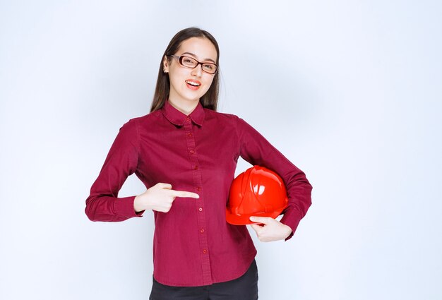 Image d'une belle femme à lunettes pointant sur un casque de protection.