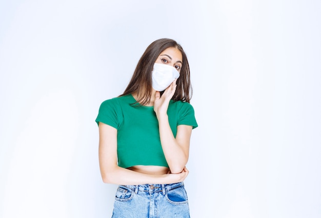 Image d'une belle jeune femme portant un masque médical en regardant la caméra.