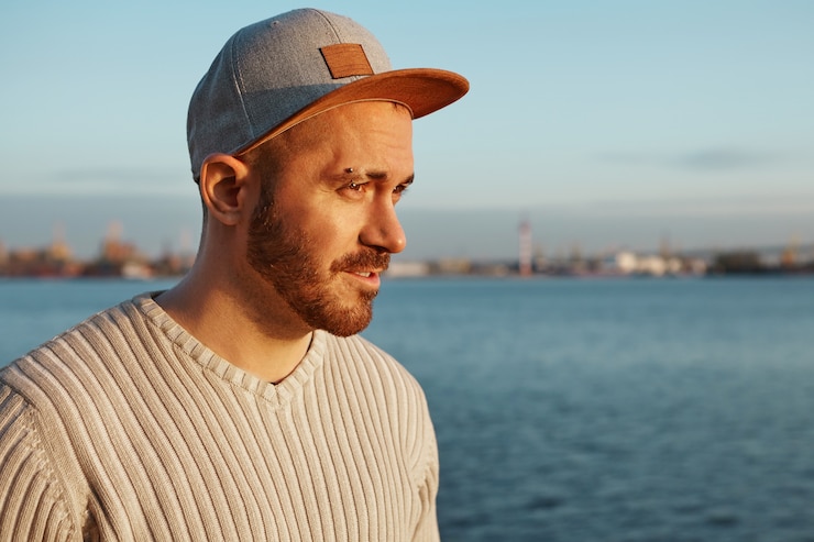 Photo gratuit image de côté de l'attrayant jeune homme mal rasé de race blanche à la mode portant élégant snapback