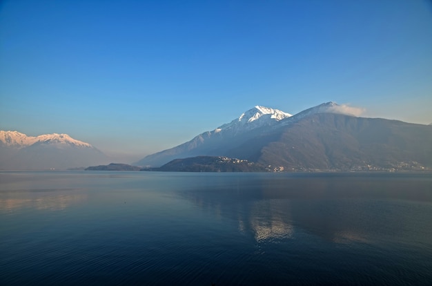 Image fascinante de montagnes enneigées se reflétant sur l'eau sous le ciel azur