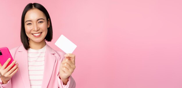 Image d'une femme d'affaires asiatique souriante et heureuse montrant une carte de crédit payant en ligne sur une application pour smartphone