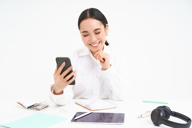 Photo gratuite l'image d'une femme d'affaires coréenne au bureau se connecte à un webinaire sur un téléphone portable parle en chat vidéo avec