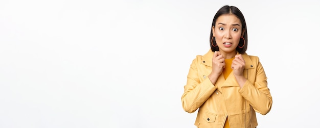 Image d'une femme asiatique effrayée qui a l'air peu sûre et inquiète devant la caméra haletant choquée debout inquiète sur fond blanc