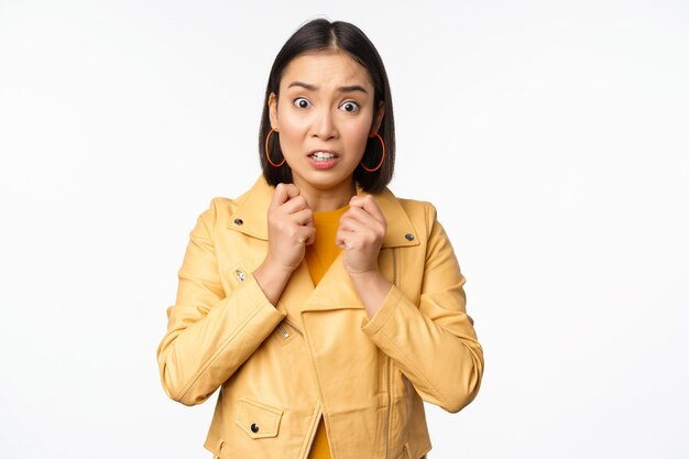 Image d'une femme asiatique effrayée qui a l'air peu sûre et inquiète devant la caméra haletant choquée debout inquiète sur fond blanc