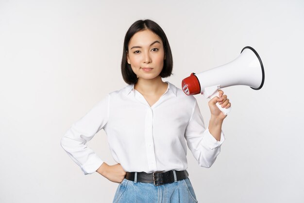 Image d'une femme asiatique moderne avec un mégaphone faisant une annonce sur fond blanc
