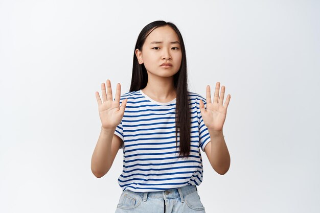 Image d'une femme asiatique sérieuse dire d'arrêter de dire non de refuser quelque chose montrant un geste de rejet interdisant l'action fond blanc