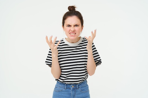 Photo gratuite image d'une femme en colère criant et se serrant la main se tient dans des vêtements décontractés sur un fond blanc