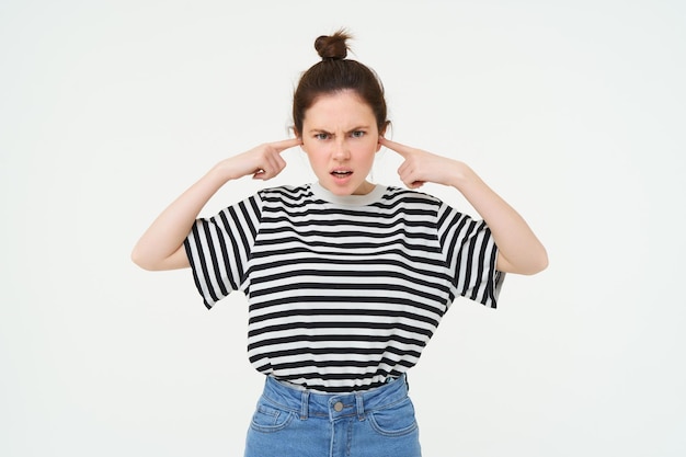 Photo gratuite l'image d'une femme ennuyée bouche ses oreilles avec des doigts dérangés par le bruit fort se tient