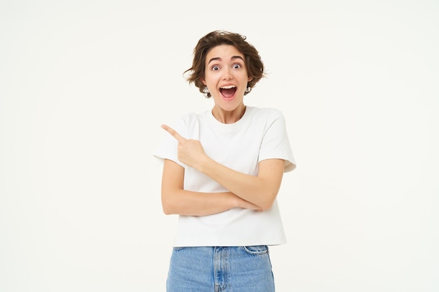 Photo gratuite image d'une femme excitée pointant le doigt vers la gauche montrant une publicité démontrant la bannière de la marque